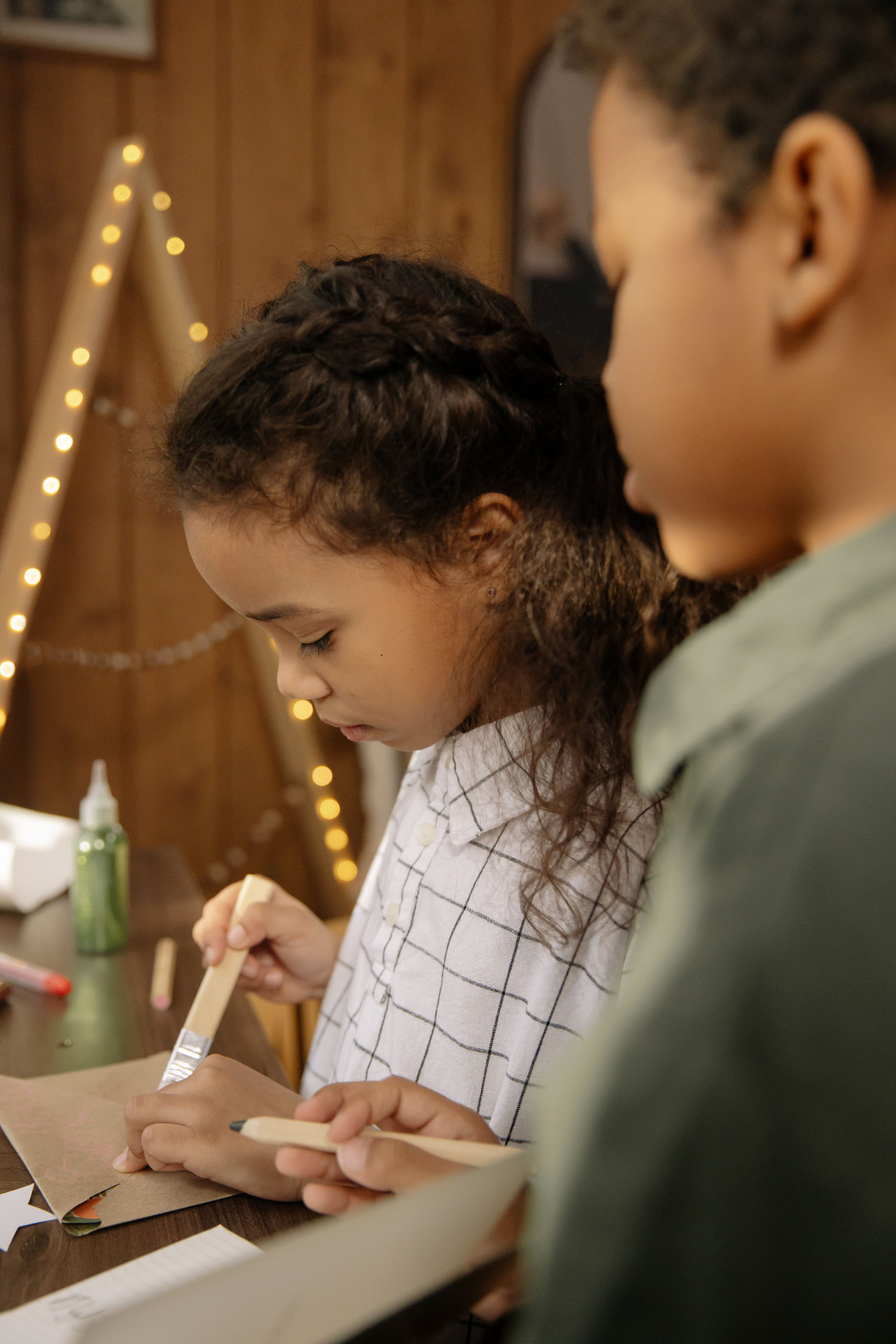 Two children painting together under warm string lights