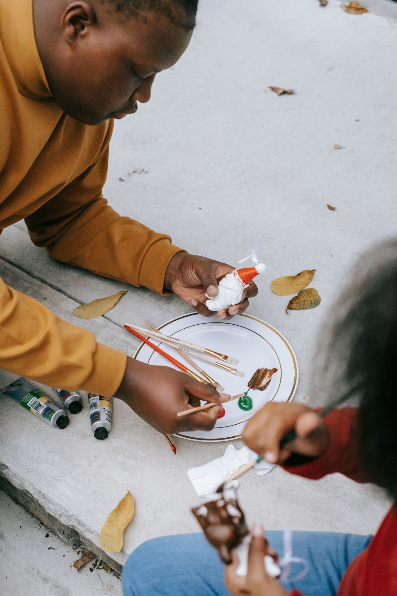 Children painting small Santa figurines with brushes and paints