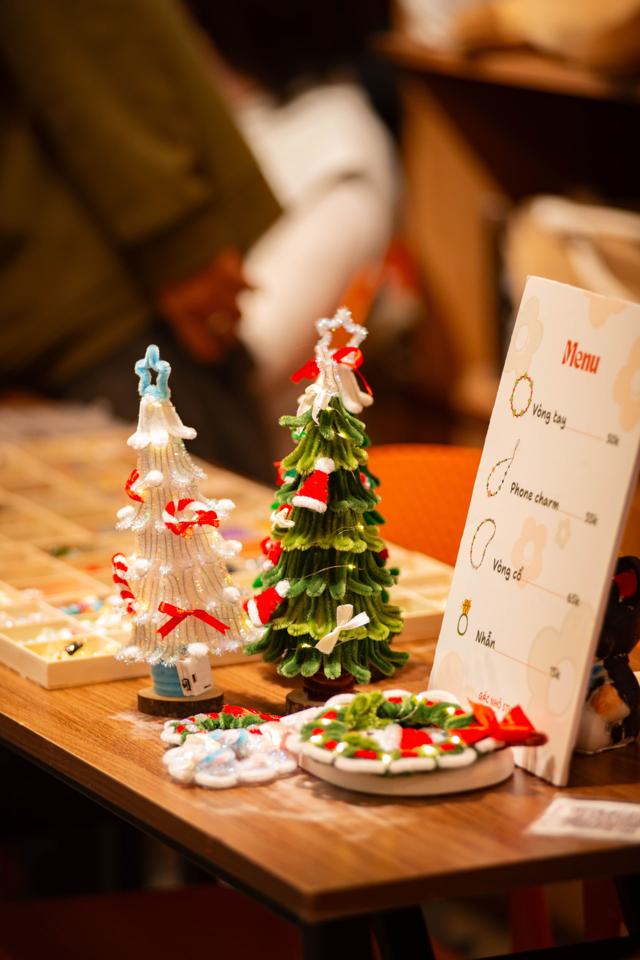 Handmade pipe-cleaner Christmas trees and wreaths on a craft market table