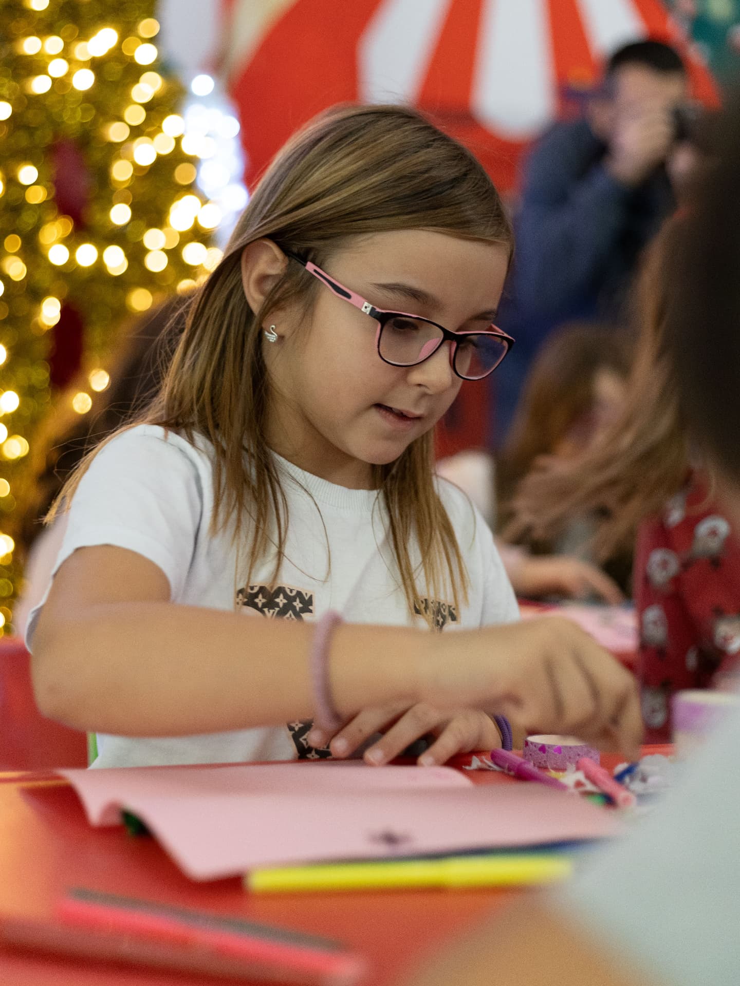 A young girl decorating paper crafts at a festive craft table