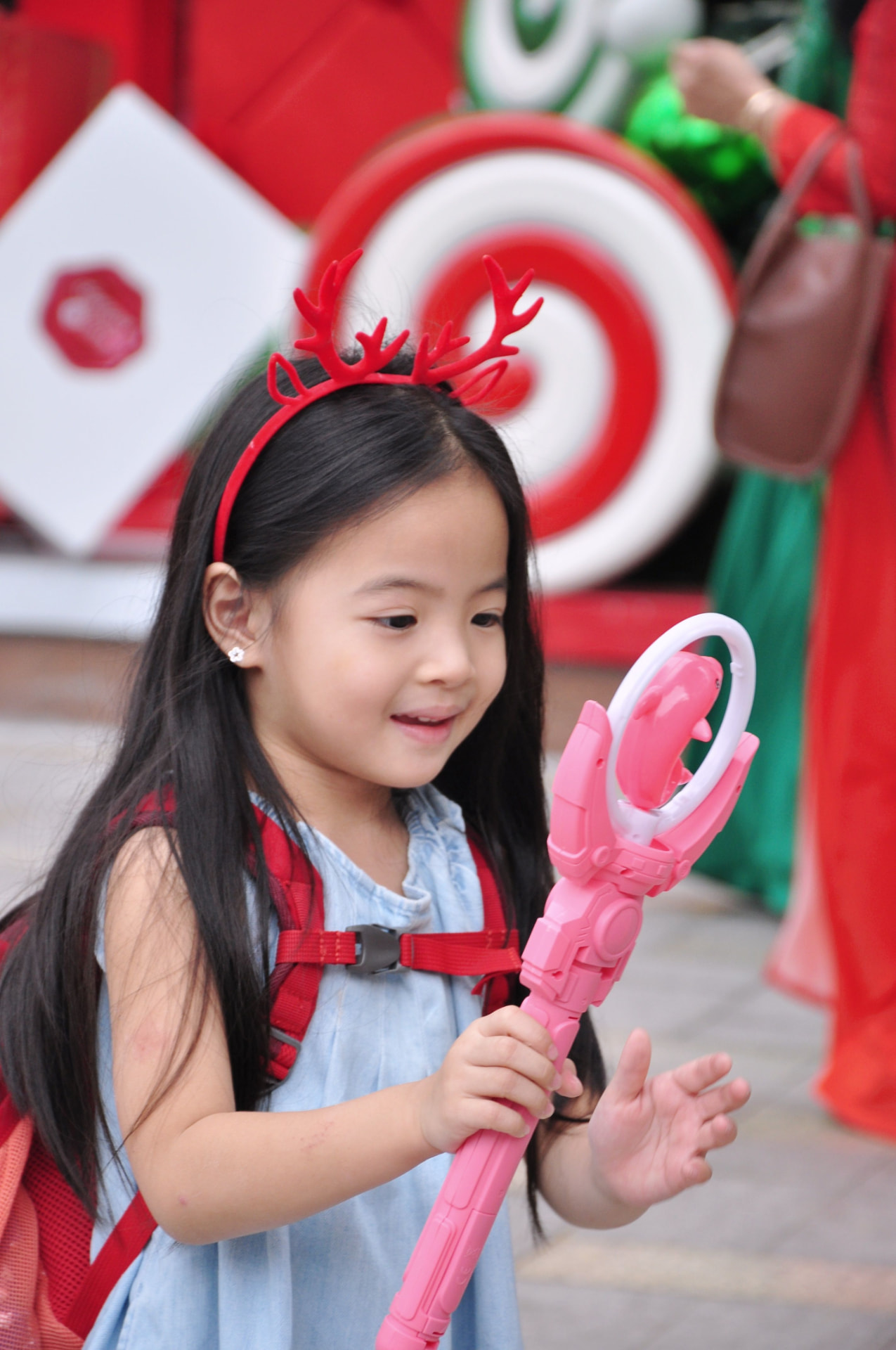 A smiling girl in reindeer antlers at a festive holiday event